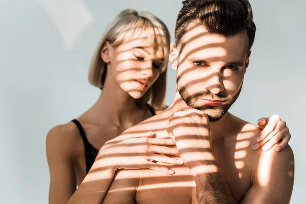 Attractive girl hugging handsome shirtless man isolated on grey with shadows — Stock Photo