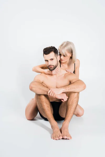 Beautiful seductive woman hugging handsome man isolated on grey — Stock Photo