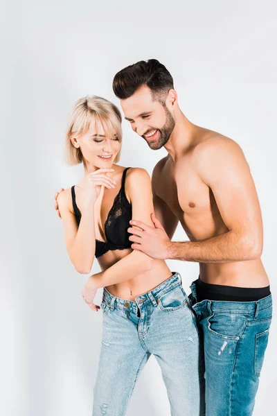 Casal feliz em roupa interior e jeans se divertir isolado em cinza — Fotografia de Stock