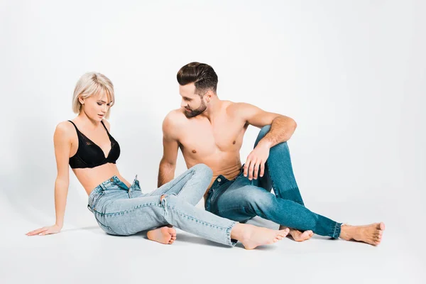 Handsome man and beautiful woman posing in underwear and jeans on grey — Stock Photo