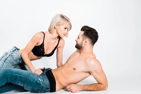 Seductive couple in underwear and jeans lying on grey — Stock Photo