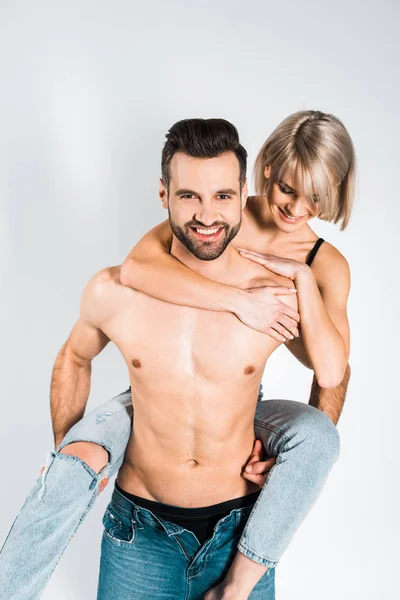 Sorridente senza maglietta fidanzato piggybacking bella ragazza felice isolato su grigio — Foto stock