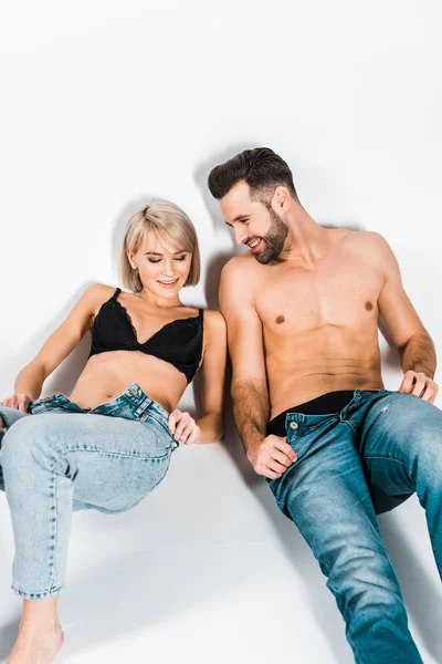 Sexy hemdloser Mann und attraktive Frau ziehen Jeans auf grau aus — Stockfoto