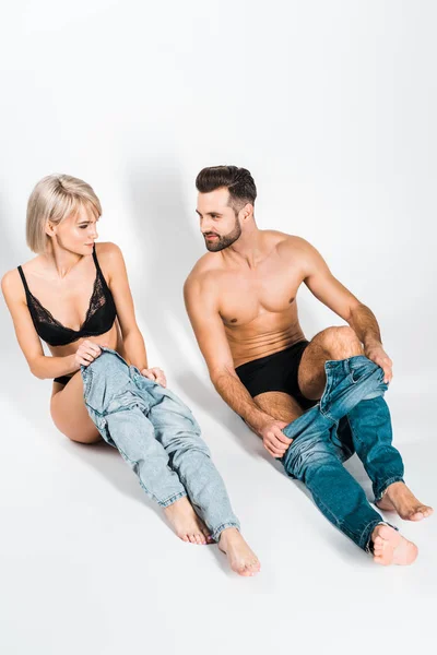 Handsome bearded man and smiling young woman wearing jeans on grey — Stock Photo
