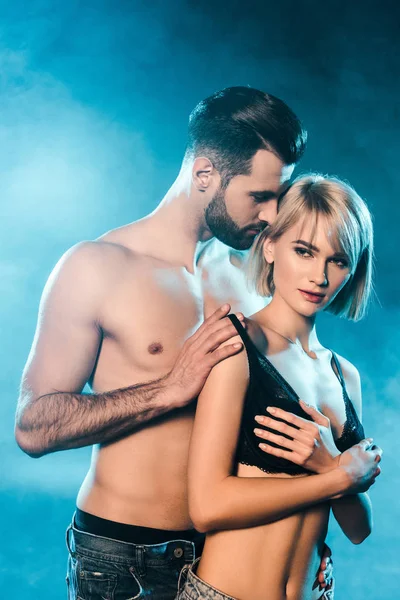 Attraktives Paar umarmt sich auf blauem rauchigen Hintergrund — Stockfoto