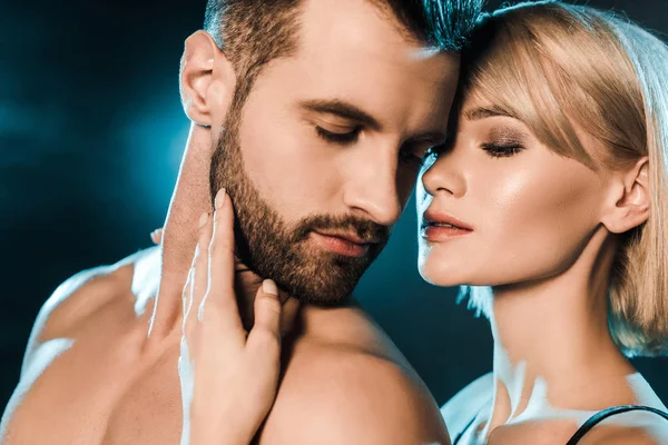 Tierna pareja abrazando con los ojos cerrados sobre fondo ahumado azul - foto de stock