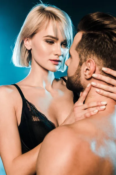 Handsome man hugging blonde girlfriend on blue smoky background — Stock Photo