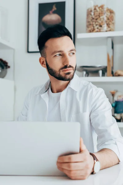 Nachdenklicher Mann mit Bart nutzt Laptop zu Hause — Stockfoto