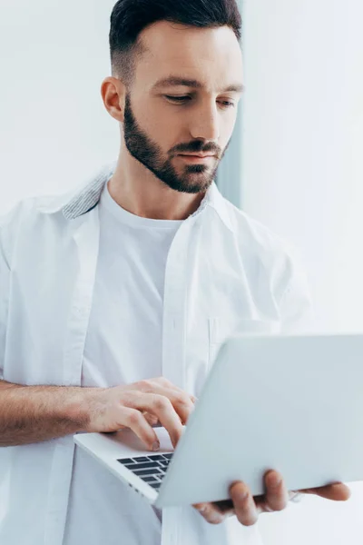 Beau jeune homme avec barbe tenant ordinateur portable — Photo de stock