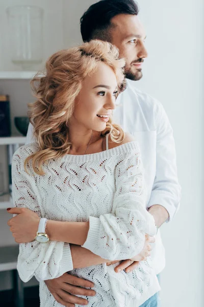 Улыбающаяся кудрявая девушка в свитере обнимается с парнем — стоковое фото