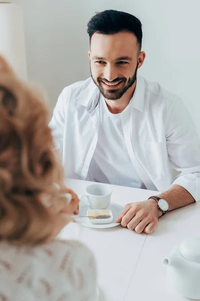 Сміється бородатий чоловік п'є каву з дівчиною — стокове фото