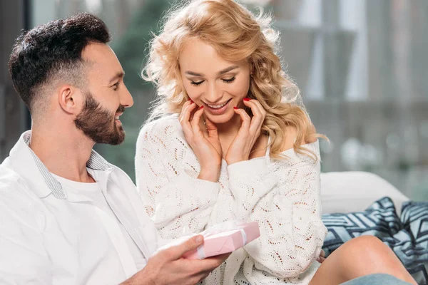 Mann mit Bart überreicht Geschenk an lächelnde Freundin — Stockfoto