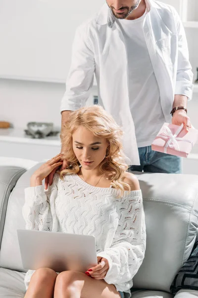 Partial view of man in white shirt presenting gift to girl with laptop — Stock Photo