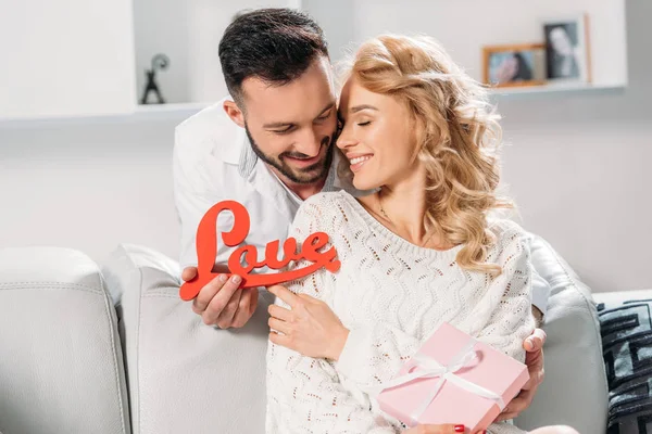 Romántico sonriente pareja sosteniendo rojo palabra amor - foto de stock