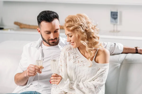 Casal romântico sentado no sofá e bebendo champanhe — Fotografia de Stock