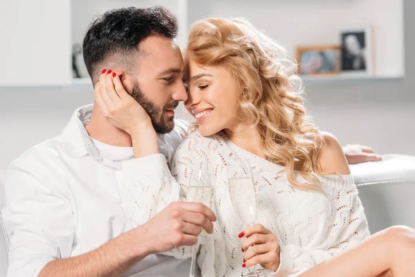 Blissful sonriente pareja beber champán en casa - foto de stock