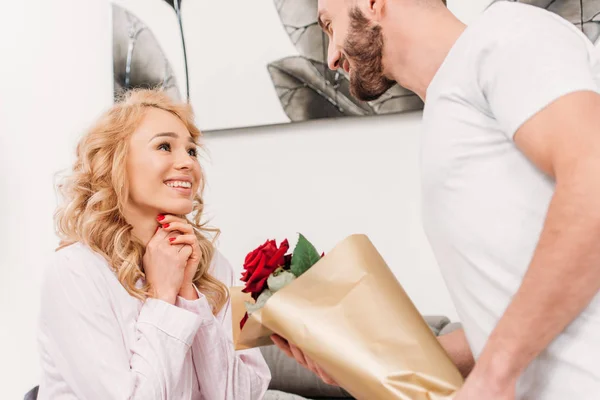 Man in white t-shirt presenting flowers to girlfriend — Stock Photo