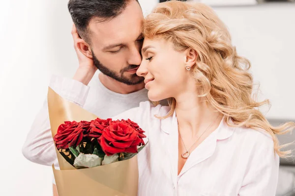 Curly mulher loira com rosas suavemente tocando namorado — Fotografia de Stock