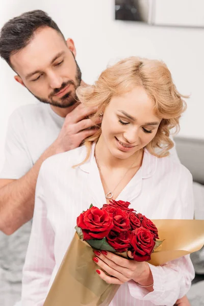 Heureux couple romantique posant avec des roses rouges — Photo de stock