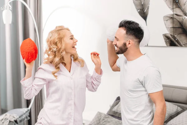 Casal rindo olhando um para o outro e segurando corações de brinquedo — Fotografia de Stock