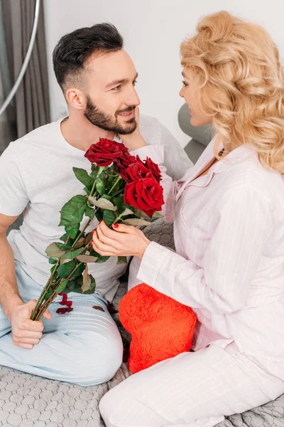 Happy couple posing with toy heart and red roses — Stock Photo