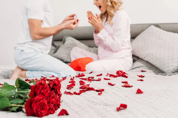 Cropped view of man sitting on bed and making proposal to girlfriend — Stock Photo