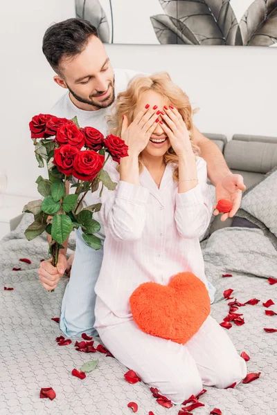 Uomo che fa proposta e presenta fiori alla fidanzata in camera da letto — Foto stock
