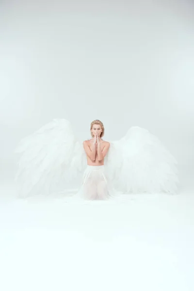 Belle femme aux ailes d'ange faisant un geste de prière et regardant la caméra isolée sur blanc — Photo de stock