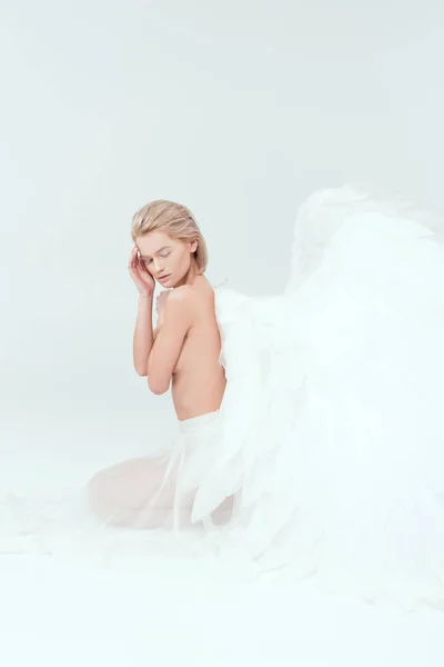 Beautiful woman with angel wings sitting with eyes closed isolated on white — Stock Photo