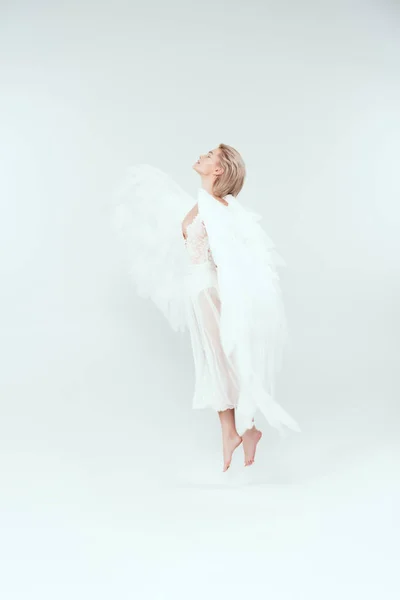 Bela mulher em traje de anjo com asas pulando isolado no branco — Fotografia de Stock