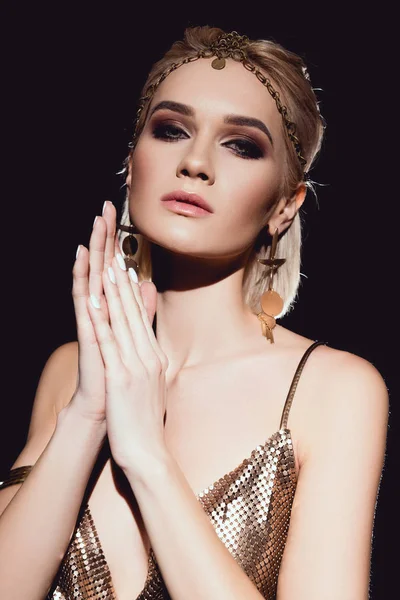 Beautiful woman in golden accessories posing and looking at camera isolated on black — Stock Photo