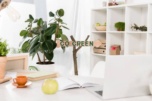 Workspace with apple and laptop near go green sign in modern office, environmental saving concept — Stock Photo