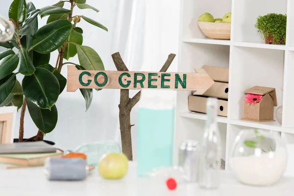 Foco seletivo do sinal de madeira com go green lettering perto do local de trabalho no escritório, conceito de economia ambiental — Fotografia de Stock