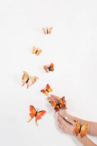 Zugeschnittene Ansicht einer Frau in der Nähe orangefarbener Schmetterlinge auf weißem Hintergrund, Umweltschutzkonzept — Stockfoto