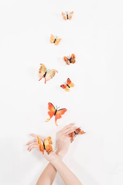 Cropped view of woman with crossed arms near orange butterflies flying on white background, environmental saving concept — Stock Photo