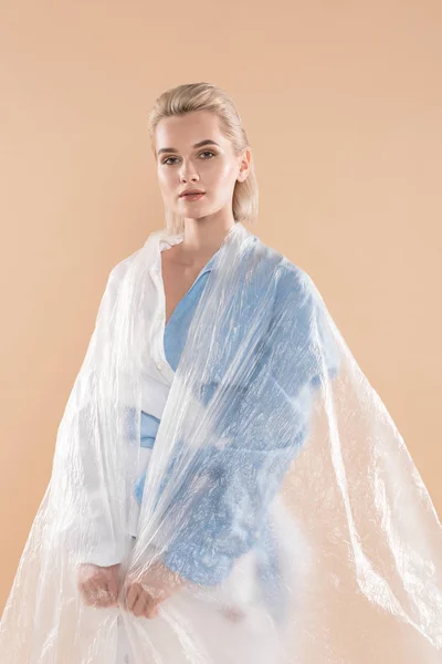 Frau steht in Öko-Kleidung in Polyethylen-Isolation auf beigem, umweltfreundlichem Konzept — Stockfoto