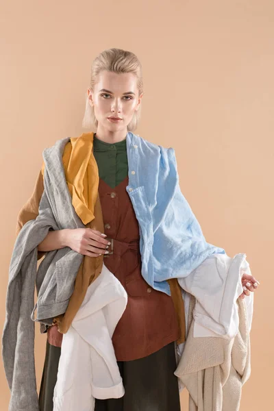Mujer atractiva sosteniendo ropa ecológica aislada en beige, concepto de ahorro ambiental - foto de stock