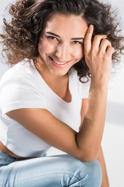 Affascinante ragazza riccia sorridente e toccante capelli — Foto stock