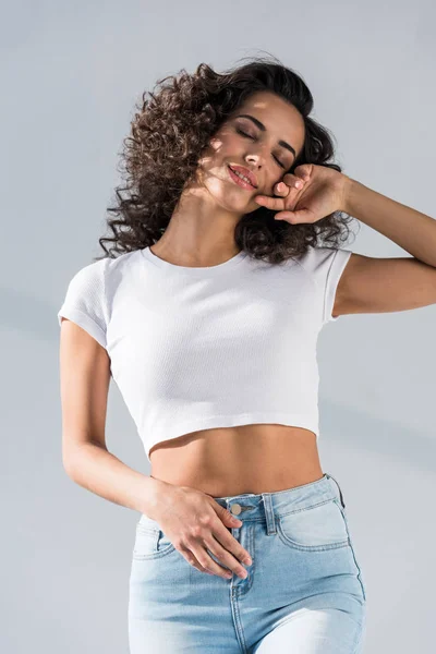 Wonderful brunette girl in jeans posing with closed eyes on grey background — Stock Photo