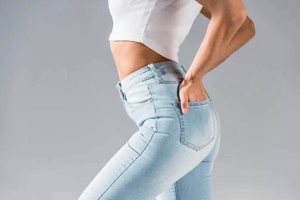 Foto recortada de chica sexy en jeans con las manos en bolsillos aislados en gris - foto de stock