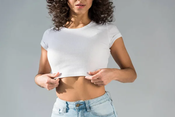 Cropped view of sexy curly woman in crop top isolated on grey — Stock Photo