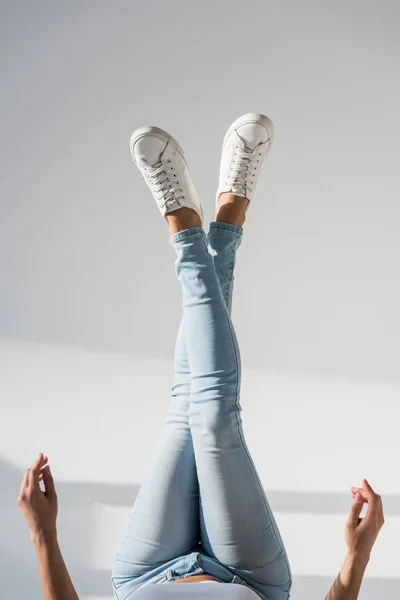 Vista parcial de la mujer en jeans azules sobre fondo gris - foto de stock