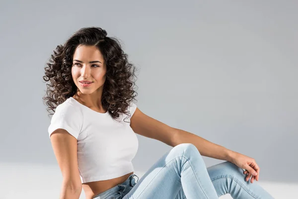 Stunning curly girl in crop top sitting on grey background — Stock Photo