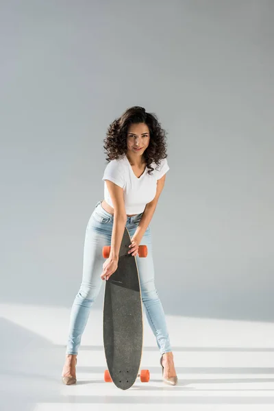 Visão de comprimento total da mulher encantadora com longboard no fundo cinza — Fotografia de Stock
