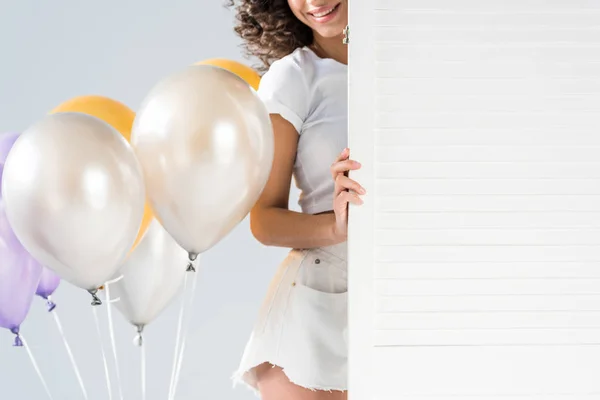 Partial view of curly woman with air balloons on grey background — Stock Photo