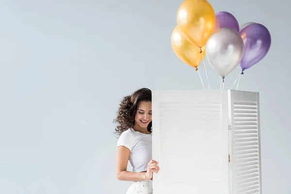 Chica rizada feliz con globos de aire sonriendo sobre fondo gris — Stock Photo