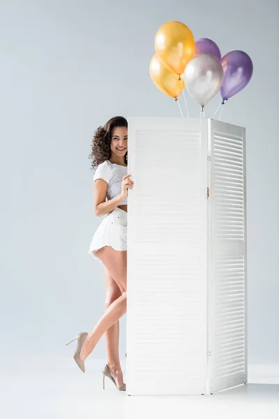 Elegant curly girl with air balloons posing on grey background — Stock Photo