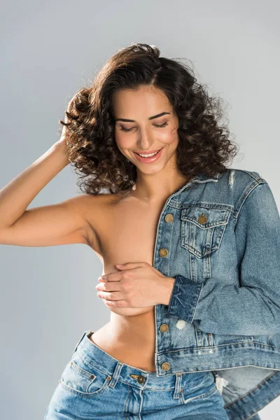 Ridendo ragazza in topless jeans toccare i capelli isolati su grigio — Foto stock