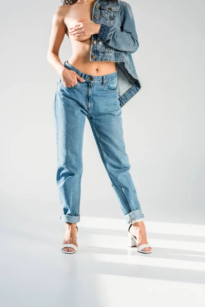 Partial view of topless woman in jeans with hand in pocket on grey background — Stock Photo