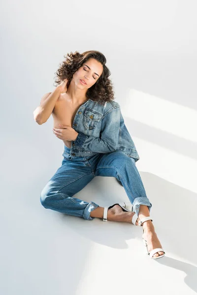 Sensual topless girl in jeans posing on floor with closed eyes — Stock Photo